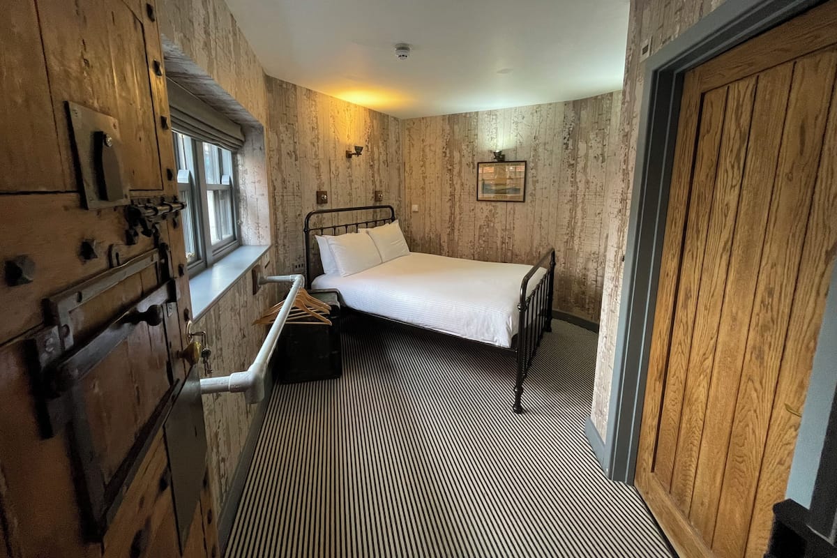 A room with a bed, a window, a wooden wardrobe, and a radiator.