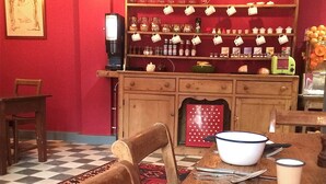 A dining area with a checkered floor, a wooden table with a bowl and cutlery, a red polka dot tablecloth, and a shelf with kitchen items. - The Black Hole (Winchester)