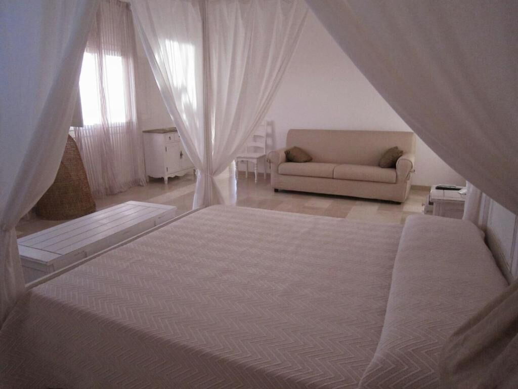 Un dormitorio con una cama grande, un sofá y una mesita.