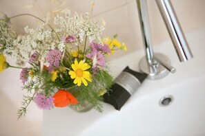A bathroom with a white sink, a faucet, and a vase of flowers. - Antica Masseria Ficazzana (Salve)