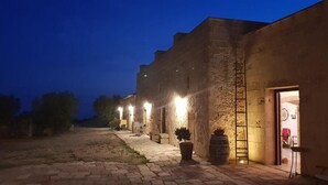 A courtyard with a stone building, outdoor seating, and a ladder leading to a door. - Antica Masseria Ficazzana (Salve)