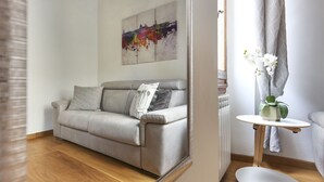 A modern living room with a grey sofa, a small round table, and a wall-mounted painting.