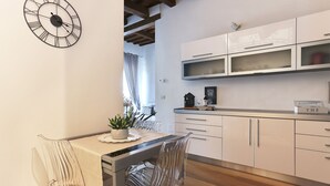 A modern kitchen with white cabinets, a clock, and a dining area with a table and chairs.