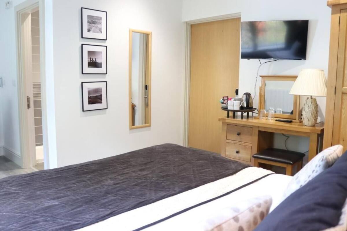 Un dormitorio con cama, cómoda, espejo, televisor y cuadros en la pared.