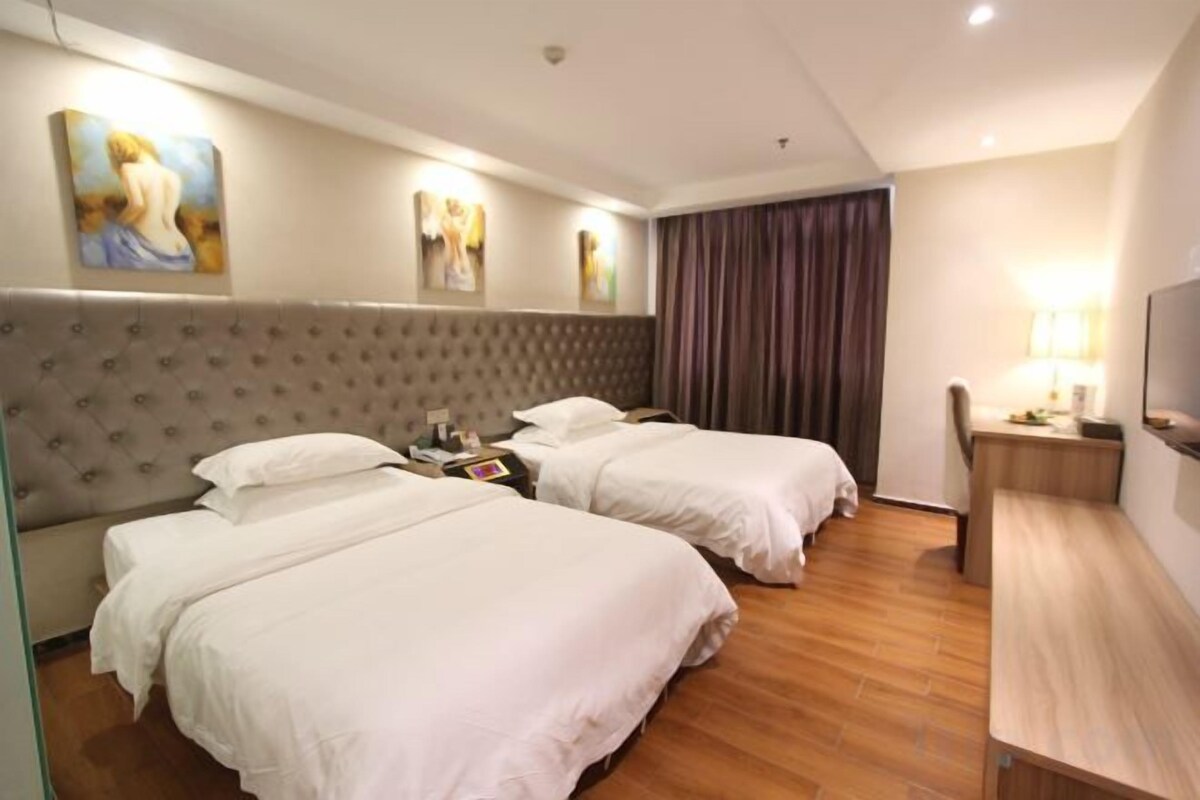 A hotel room with two beds, a desk, a chair, and a television.