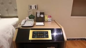 A hotel room with a bed, a bedside table with a telephone, a small card, and a box of tissues. - Wisdom Hotel (Maoming)