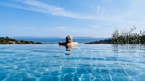 A person relaxing in a clear infinity pool with a view of the sea and distant mountains. - Villa Thalassa Art' B&B (Le Lavandou)