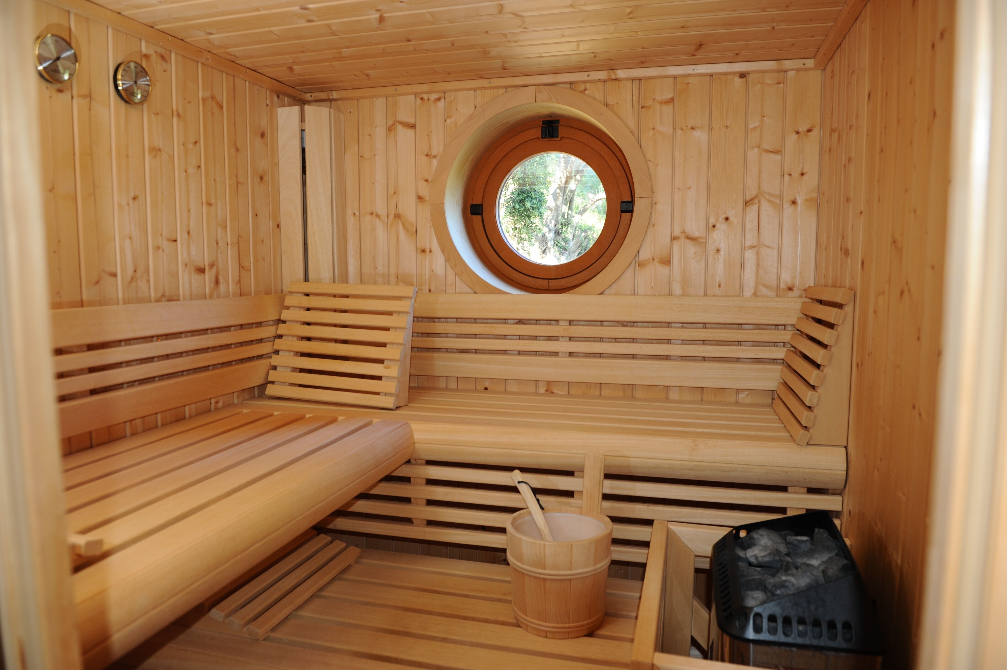 Un sauna en bois, doté de bancs et d’une fenêtre circulaire.