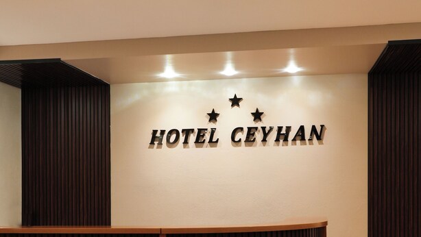 Un comptoir d’accueil avec une enseigne indiquant « HÔTEL CEYHAN » et trois étoiles au-dessus.