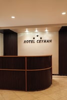 Bancada de recepção com uma placa que diz "HOTEL CEYHAN" e três estrelas acima.