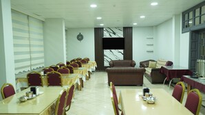 Une salle de conférence équipée de plusieurs tables et chaises, d’un canapé et d’un écran de télévision.