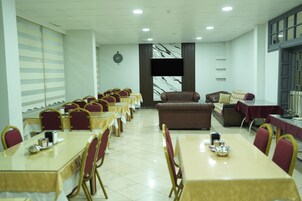 Sala de conferências com várias mesas e cadeiras, um sofá e uma tela de televisão.