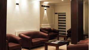 Un espace d’attente moderne avec des canapés en cuir, une table basse et un comptoir d’accueil.