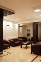Uma área de espera moderna com sofás de couro, uma mesa de centro e um balcão de recepção.