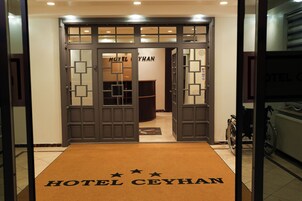Entrada de um hotel com carpete marrom e o nome "HOTEL CEYHAN" em letras grandes.