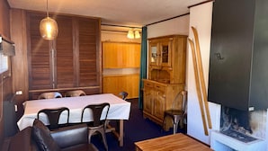 A compact room with a dining table, chairs, a sofa, a cabinet, and a fireplace.