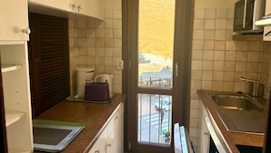A compact kitchen with a window view, a sink, and a microwave.
