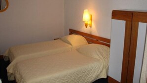 A hotel room with two single beds, a wooden headboard, a wall-mounted lamp, and a mirror on the left wall. - Cozy 2-room south in Tignes with wifi, near slopes (Tignes)