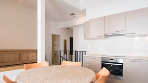 A modern kitchen with white cabinets, a built-in oven, and a dining area with a round table and orange chairs. - Renovated 3-room duplex at the foot of the slopes with WiFi in Tignes (Tignes)