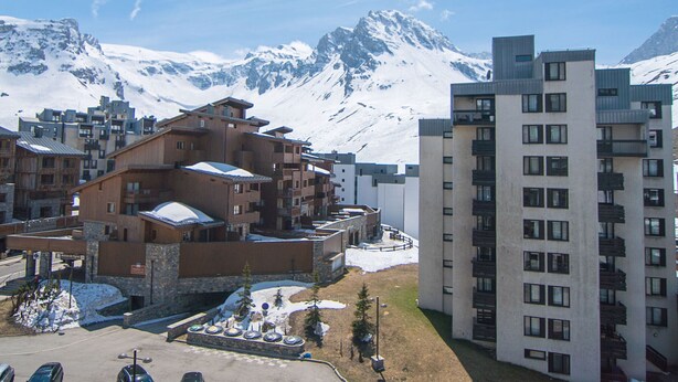 Un hôtel composé de plusieurs bâtiments, dont une imposante structure en bois dotée d’un toit en pente et un immeuble moderne à étages avec des balcons.