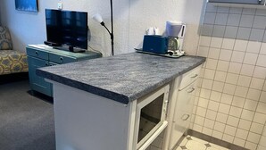 Eine kleine Küche mit einer Granitarbeitsplatte, einem eingebauten Ofen und einer Kaffeemaschine auf der Arbeitsfläche.