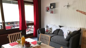 Una sala de estar acogedora con comedor, que incluye un sofá, sillas, una mesa con alimentos para el desayuno y vistas a través de una ventana.