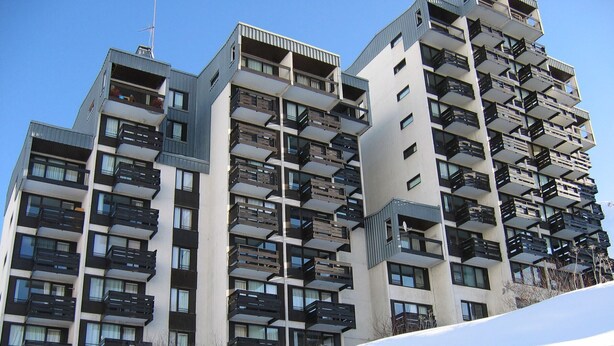 Un edificio residencial alto con varios balcones y ventanas.