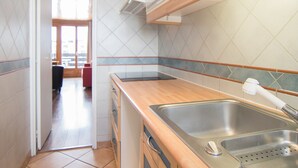 Una cocina con armarios de madera, un lavamanos de acero inoxidable y un microondas.