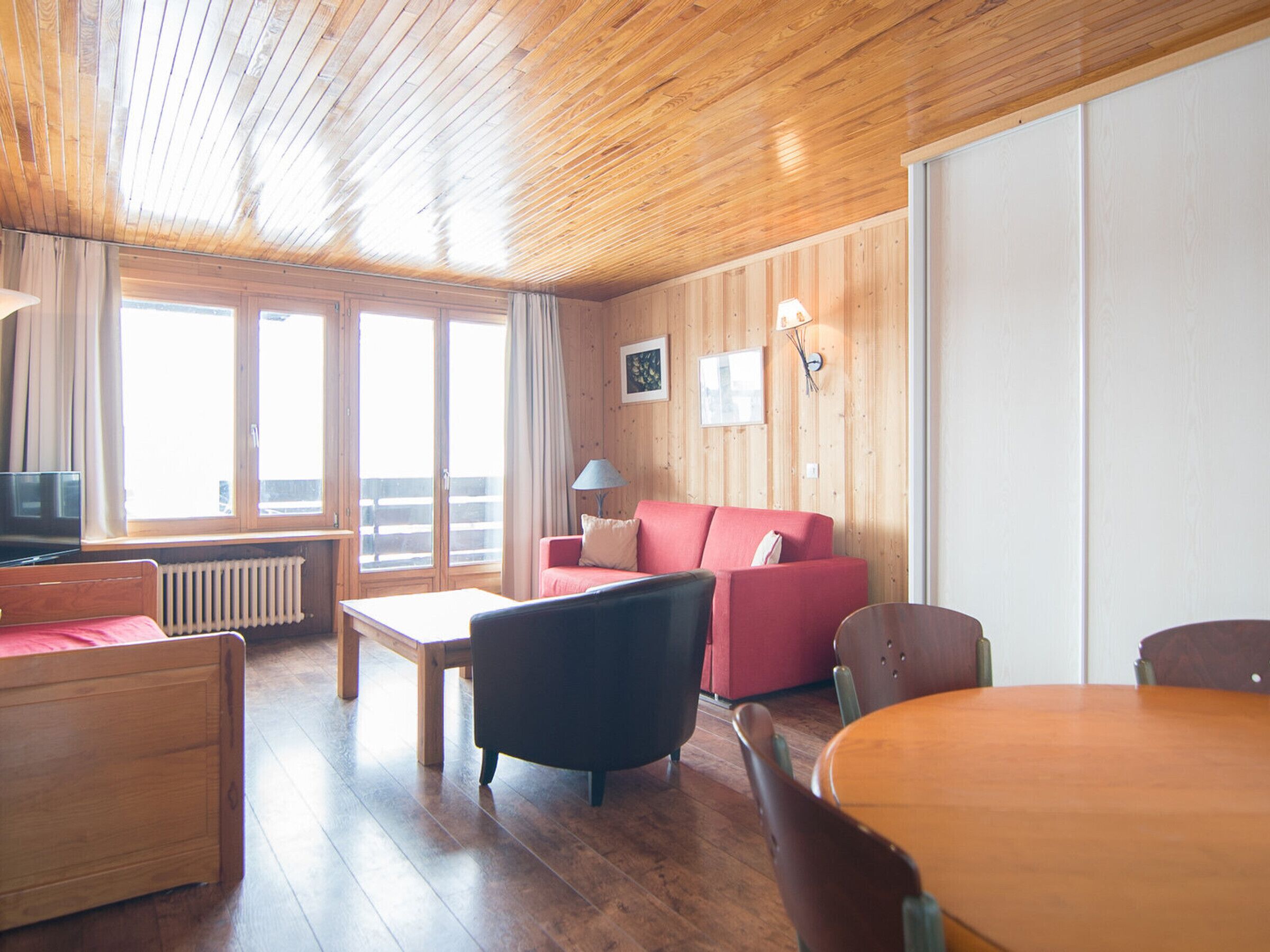 A wooden-paneled room with a sofa, a table, and a TV.