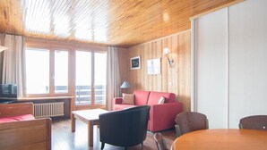 Una habitación con paneles de madera, un sofá, una mesa y un televisor.