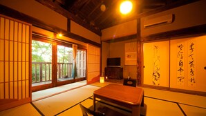 A traditional Japanese room with tatami flooring, a low wooden table, sliding doors, and a television. - Yufuin TAGASODE (Yufu)
