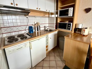 A compact kitchen with a gas stove, a microwave, a coffee maker, and a toaster. - Southwest studio, ski-in/ski-out, 30m², sleeps 4 (Tignes)