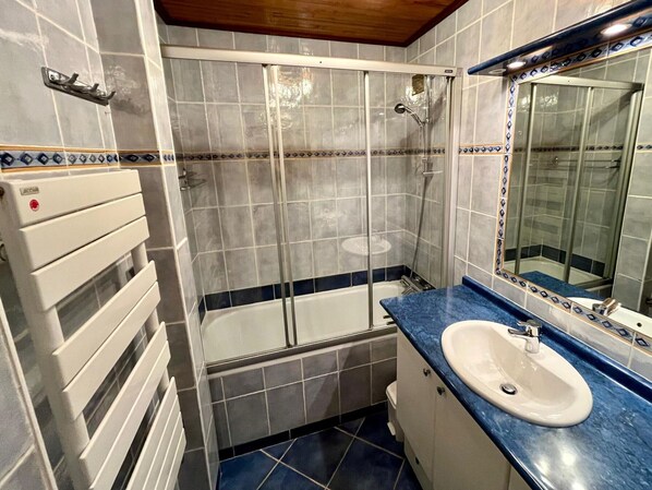 A bathroom with a bathtub, a shower, a sink, and a towel rack.