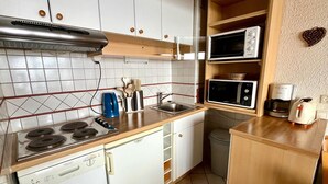 A compact kitchen with a gas stove, a microwave, a coffee maker, and a toaster.