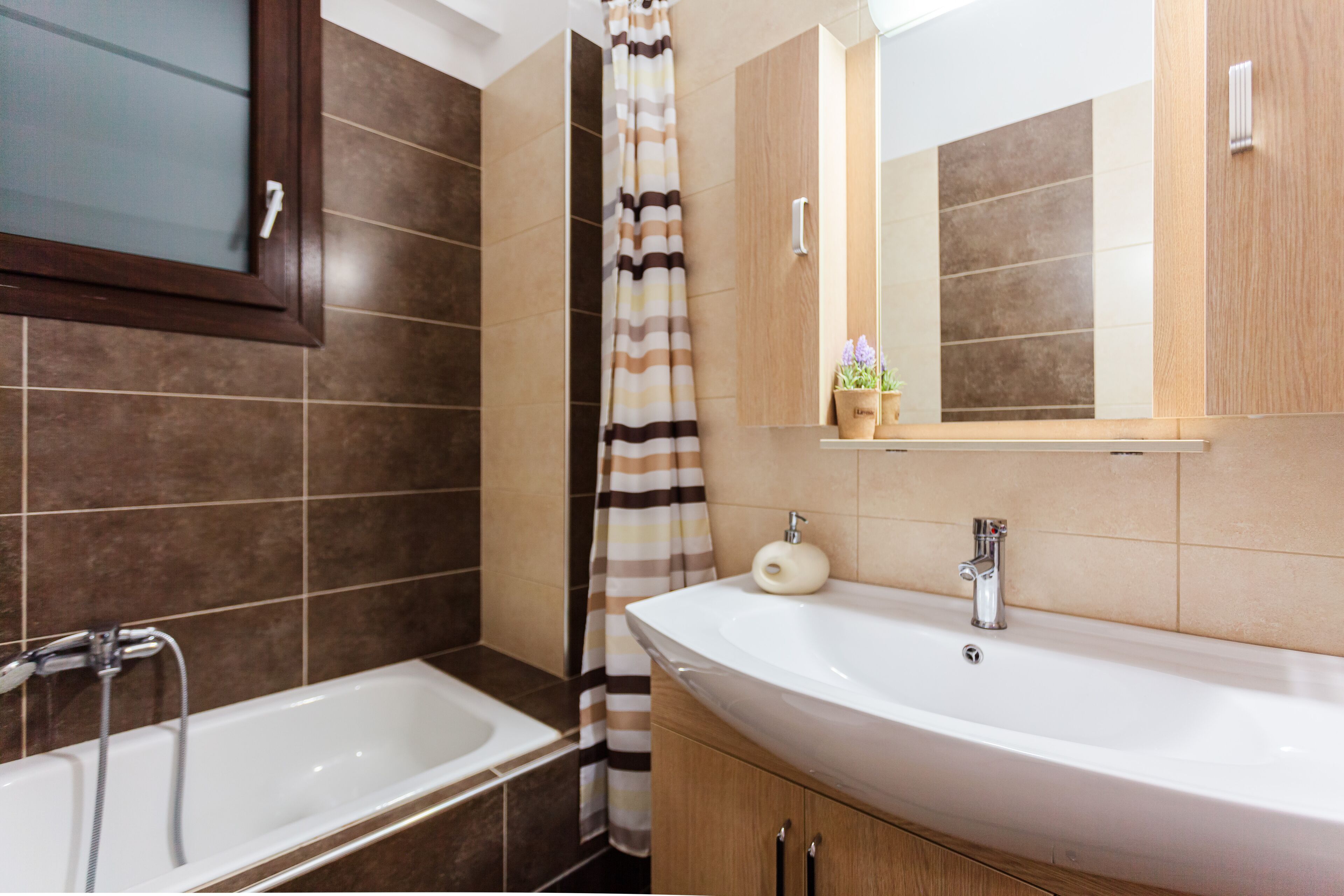 Un baño con bañera, lavamanos, espejo y cortina de ducha.