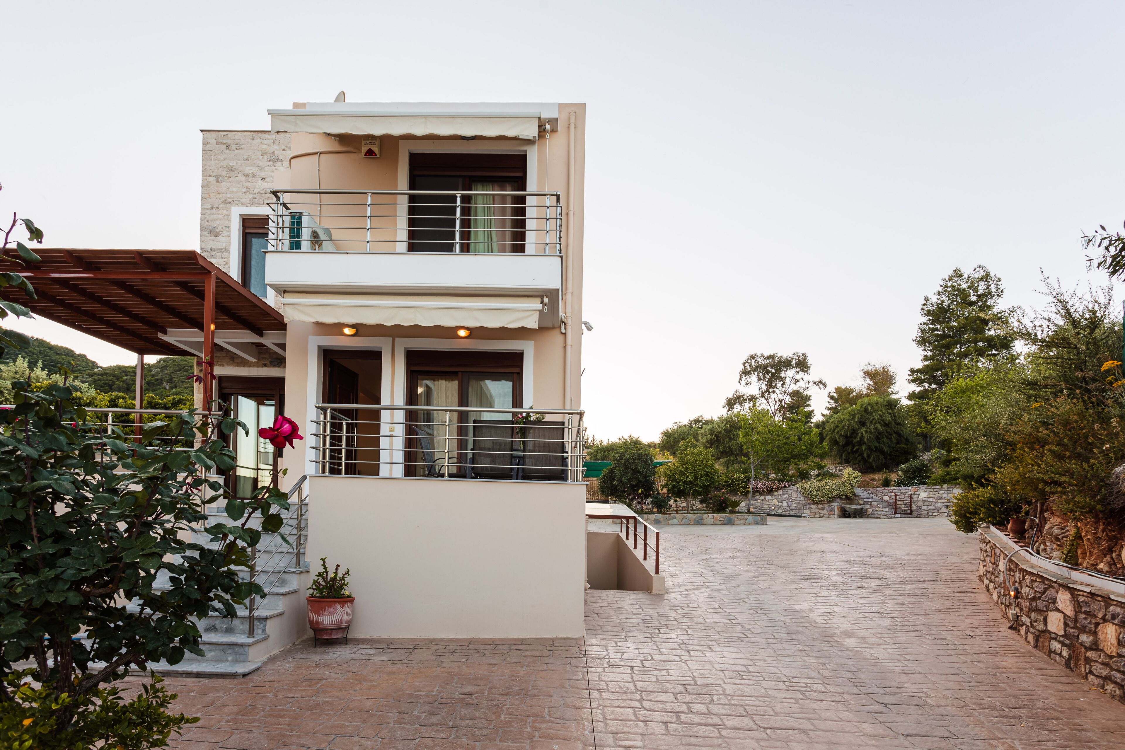 A two-story building with a balcony, a stone wall, and a paved courtyard.