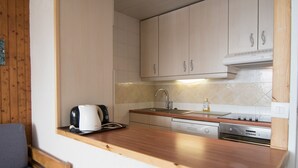A compact kitchen with wooden cabinets, a built-in stove, and a sink. - 2-Room Apartment, Near Slopes, Balcony and Free Wifi (Tignes)