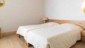 A bedroom with two single beds, a wooden headboard, a bedside table with a lamp, and a round mirror on the wall. - 2-Room Apartment, Near Slopes, Balcony and Free Wifi (Tignes)