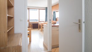 A hallway leading to a kitchen with wooden furniture and a window. - 2-Room Apartment, Near Slopes, Balcony and Free Wifi (Tignes)