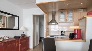 A compact kitchen with wooden cabinets, a coffee maker, and a dining area with a table and chairs. - South/West Apt 2R, 500m from slopes, Wi-Fi, Val-Claret (Tignes)