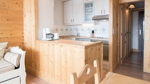 Interior de una cabaña de madera con una zona de cocina, una mesa de comedor y un sofá.