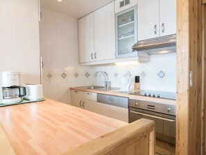 A modern kitchen with white cabinets, a stainless steel range, a dishwasher, and a coffee maker. - Cozy 1-bedroom in Tignes, mountain view, Wifi, near slopes (Tignes)