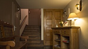 A wooden staircase leading to a landing with a wooden chair and a small table with a lamp. - Hotel Espellet (Larceveau-Arros-Cibits)