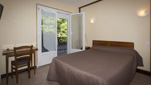 A bedroom with a bed, a desk, and a chair. There is a sliding glass door leading to an outdoor area with a view of greenery. - Hotel Espellet (Larceveau-Arros-Cibits)