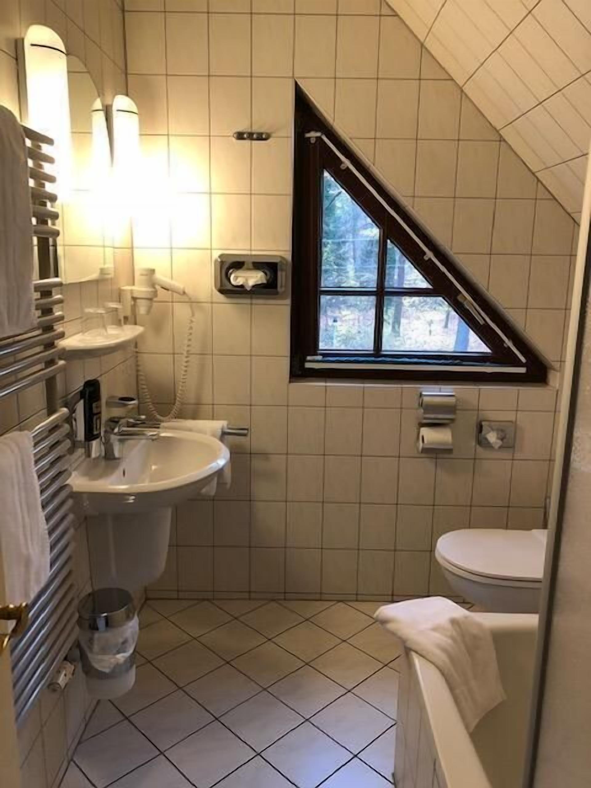 A small bathroom with a sink, toilet, and a window.