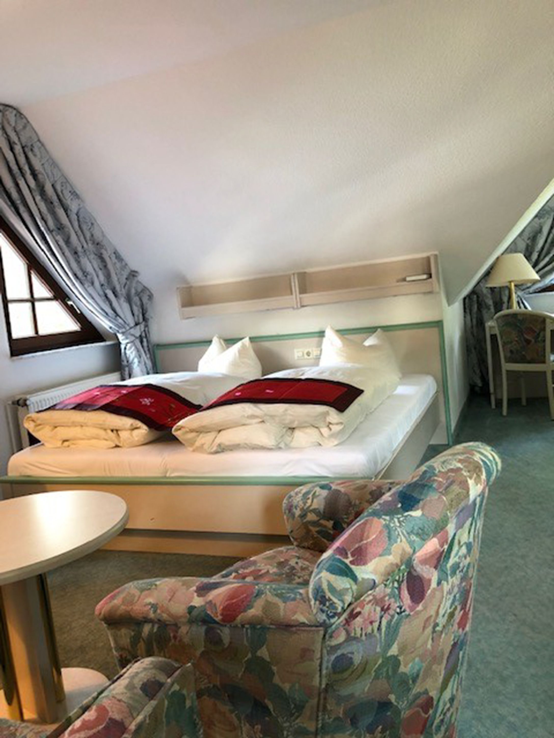 A small, cozy room with a bed, a chair, and a table.