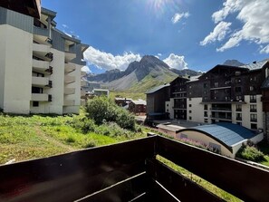 Un bâtiment moderne doté de nombreux balcons, entouré de verdure et avec des montagnes en toile de fond.