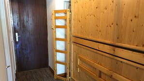 A wooden interior with a dark wooden door, a wooden ladder, and a wooden cabinet with drawers. - Luxury Studio 30 m², ski-in, balcony, perfect for 4 in Tignes (Tignes)