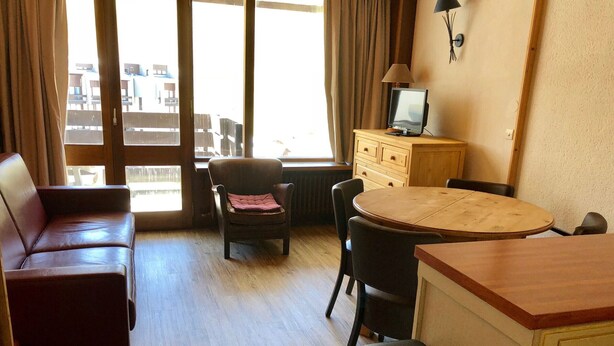 A room with a sofa, a chair, a small table, a TV on a cabinet, and a view through a large window. - Luxury Studio 30 m², ski-in, balcony, perfect for 4 in Tignes (Tignes)