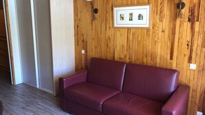 A room with a wooden wall, a framed picture, and a red sofa. - Luxury Studio 30 m², ski-in, balcony, perfect for 4 in Tignes (Tignes)